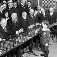 大勢の大人とチェスをする子供