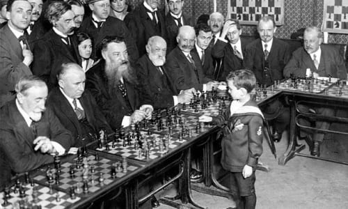 大勢の大人とチェスをする子供